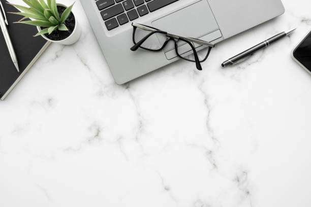 istock White marble office desk table with laptop computer and office supplies. Top view with copy space, flat lay. 1390603048