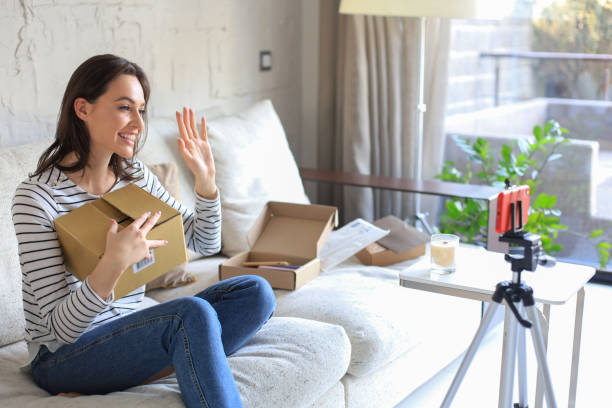 istock Young beautiful female blogger recording video while unpacking parcel at home. 1390605000