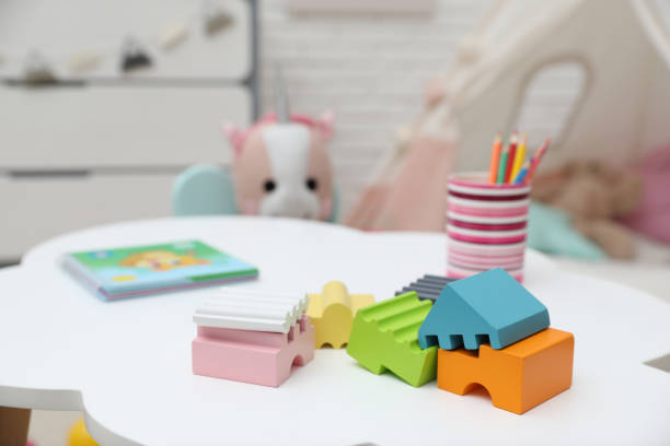 istock Bright toys, pencils and book on white table in playroom 1390606796