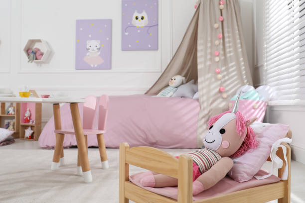 istock Cute toy unicorn on small bed in playroom, space for text. Interior design 1390609391