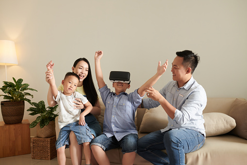 Excited family supporting happy boy winning in virtual reality game