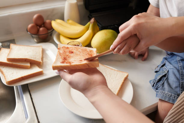 Mother and Son Spreading Bread Hands of mother teaching little son speading jam on sandwich bread making a sandwich stock pictures, royalty-free photos & images