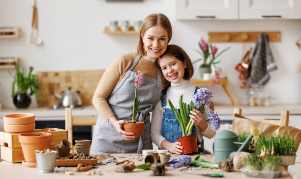 istock Optimistic mother and daughter with flowers in kitchen 1390616653