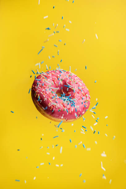 istock Donut levitating on a yellow background with decorative sprinkles. 1390621366