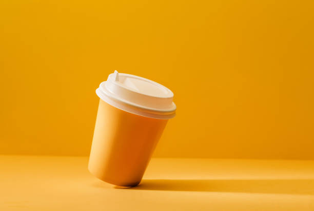 Yellow cup for coffee on a yellow background with a shadow.