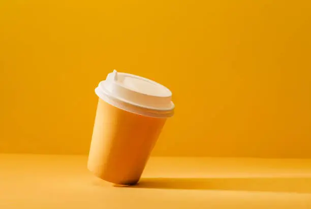Yellow cup for coffee on a yellow background with a shadow.