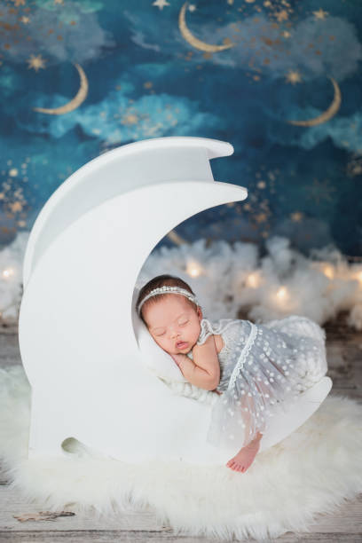Happy adorable cute Asian newborn baby sleeping on moon bed