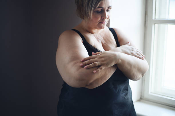 下着姿の落ち込んだ孤独な太った女性は、下を向いて家で考えています。 - mature adult sadness overweight women ストックフォトと画像