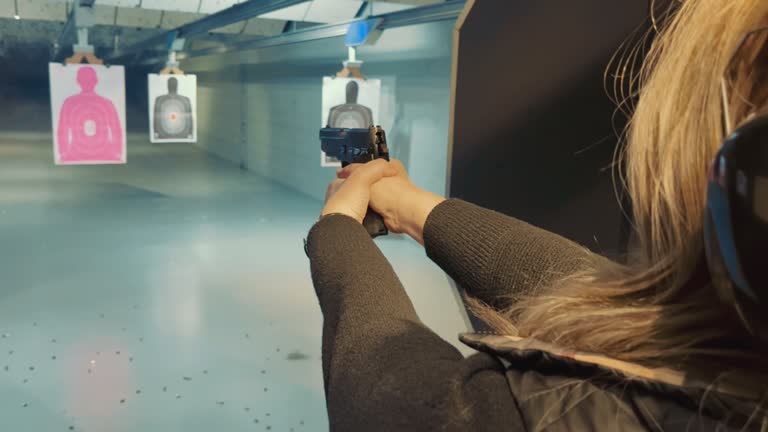 Woman shooting at a target with a pistol in a shooting range. Woman training to hit a target with a pistol. Training women police officers