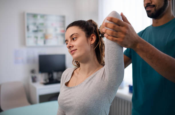 Young male physiotherapist examining young woman patient in a physic room A young male physiotherapist examining young woman patient in a physic room orthopedist stock pictures, royalty-free photos & images