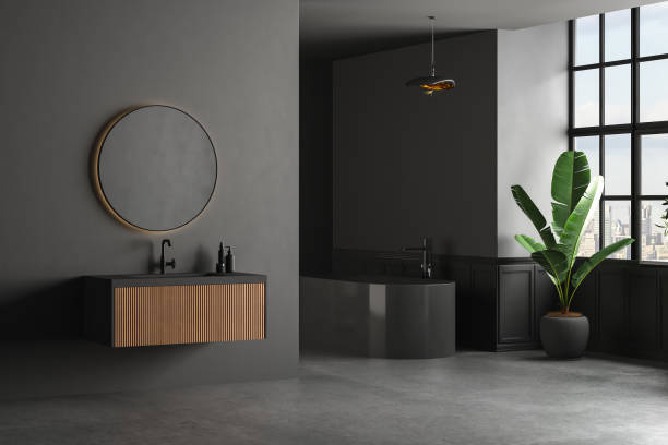 istock Dark bathroom interior with concrete floor, black bathtub, and oval mirror standing on black wall. 1390631464