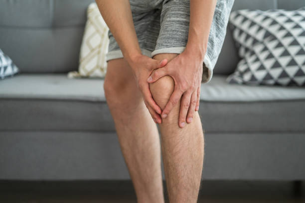 Knee pain, man suffering from ache and doing self-massage at home Knee pain, man suffering from ache and doing self-massage at home, self-soothing massaging Rickets Symptoms stock pictures, royalty-free photos & images