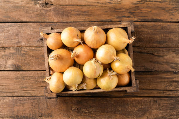 istock Fresh white onions in crate on rustic wooden table. Top view 1390634339