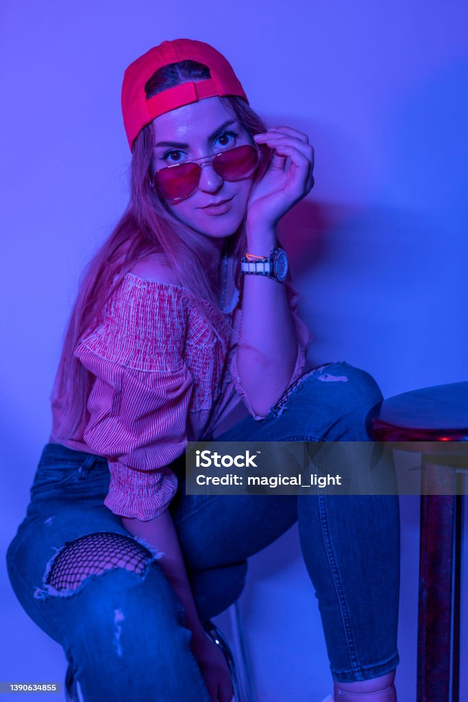 High Fashion model woman in colorful bright neon blue and purple lights posing in studio. High Fashion model woman in colorful bright neon blue and purple lights posing in studio. Portrait of beautiful woman with trendy glowing make-up. Art design vivid style 25-29 Years Stock Photo