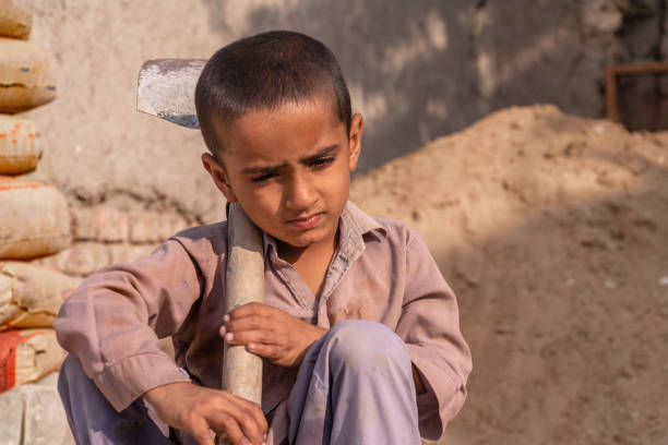 istock child boy sitting holding a shovel on a construction site 1390641566