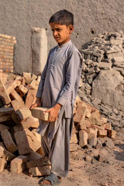 istock a child boy holding a brick in hand on working on a construction site 1390641717