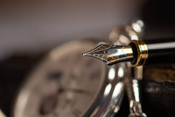 füllfederhalter, schöner füllfederhalter in einer umgebung mit einer alten uhr, altem buch, tinte unter anderem, selektiver fokus. - pen color image black book stock-fotos und bilder