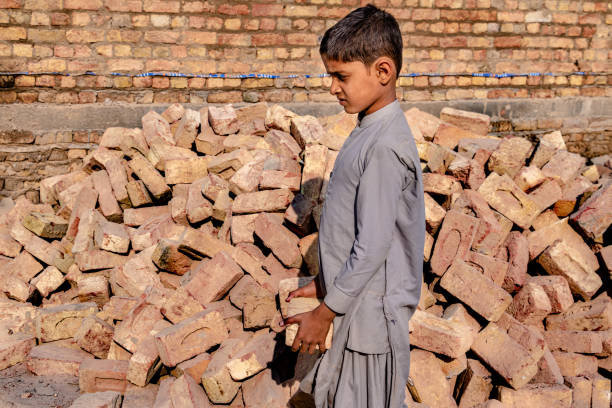 istock a child boy holding a brick in hand on working on a construction site 1390642234
