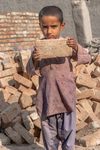 istock a child boy holding a brick in hand on working on a construction site 1390643429