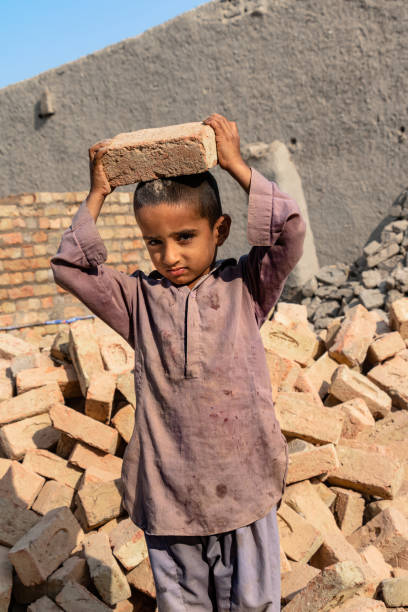 istock a child boy holding a brick in hand on working on a construction site 1390643432