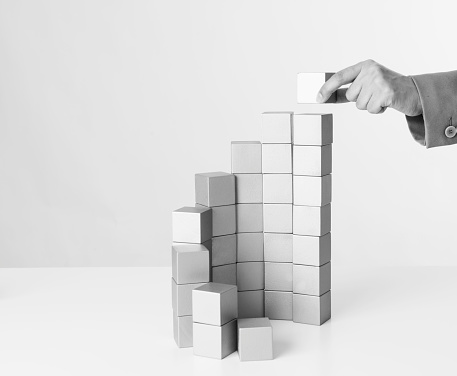 Successful business woman building a project with wooden cubes.