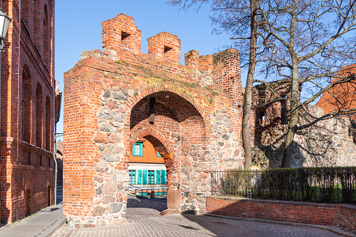 Torun, Poland - March 28, 2022: Brick gate  of an old gothic building, ancient medieval tower in Torun. Arch gate in the wall, entrance to the historical district