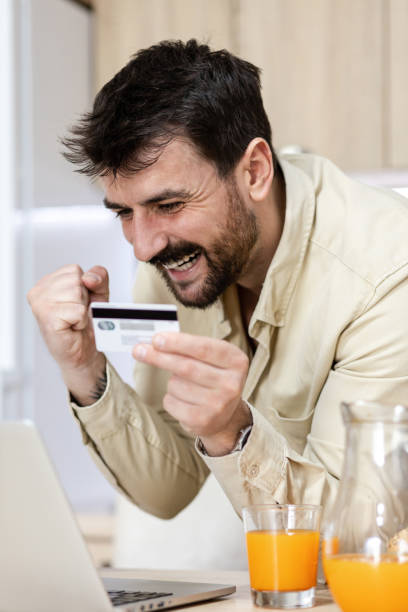 istock Young attractive man holding a credit card celebrating 1390645967