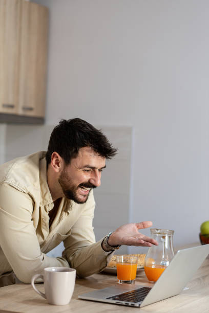 istock Attractive businessman is smiling while working on laptop at home 1390646074