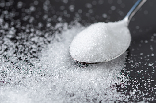 Close-up of spoon with sugar on the black table