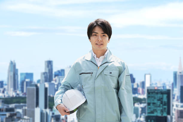 építőmunkások a város hátterében - kezeslábas témájú stock jellegű vizuális alkotások, jogdíjmentes fotók és képek