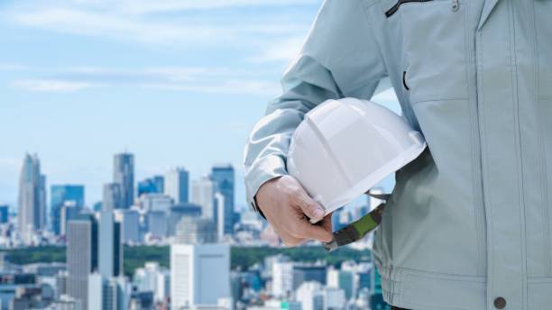 trabajadores de la construcción en el contexto de la ciudad - casco de trabajo fotografías e imágenes de stock