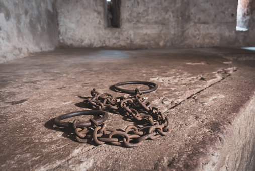 Ancient handcuffs in slave cell. Cage for slaves. African slave market. Interior of slave jail with rusty handcuffs. Humanity concept. Memorial of slave victims.