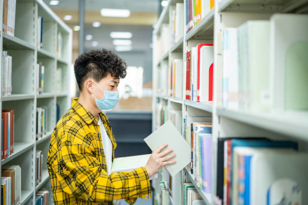 istock Asian adult student borrowing books in library 1390650694