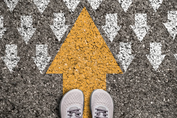 istock Different thinking and Business and technology disruption concept. Yellow big arrow opposite  direction with white arrow on road asphalt. 1390650801