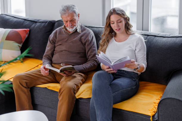 istock Handsome charming bearded senior man and his granddaughter focused reading book while sitting on the sofa in the living room at home. 1390652547