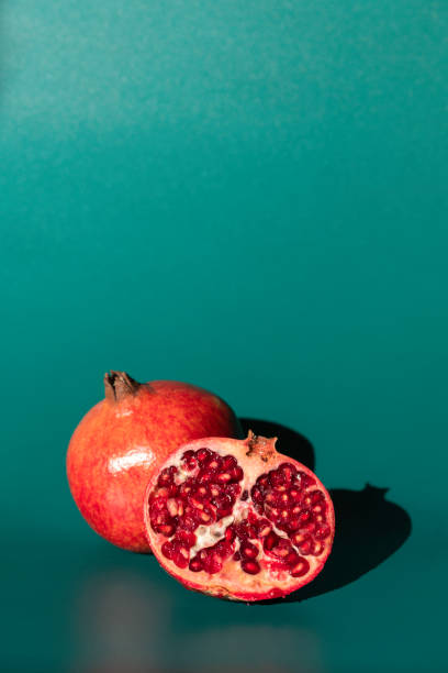 Pomegranate on an emerald background One whole and one cut pomegranate on an emerald background with shadows emerald green photos stock pictures, royalty-free photos & images