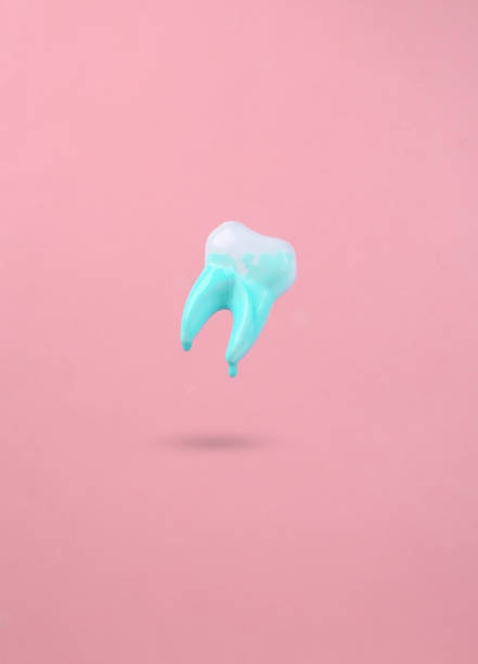 istock Levitating tooth with dripping turquoise paint on a pink background. Minimal creative layout. Concept art. 1390653705