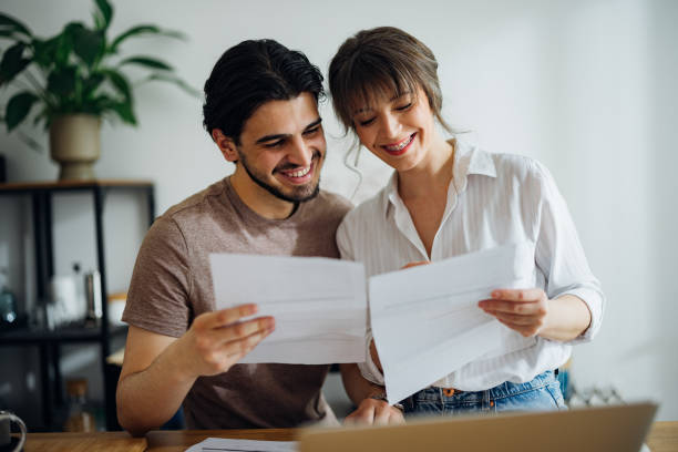 istock Cheerful Couple Paying Bills at Home 1390654315