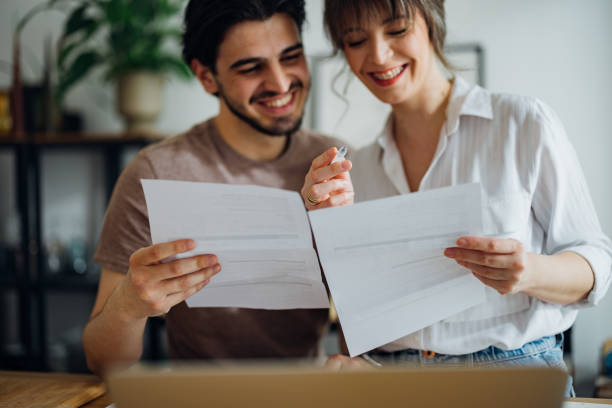 istock Cheerful Couple Paying Bills at Home 1390654317