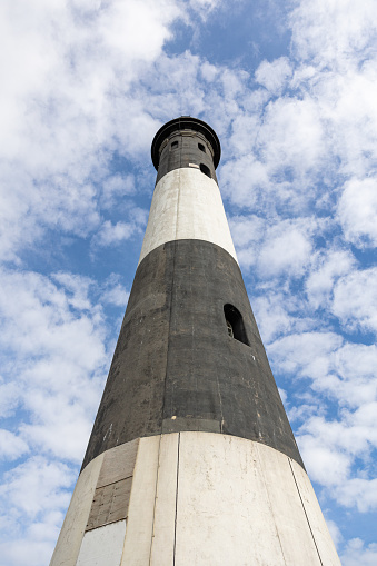 Tall stone lighthouse under a beautiful blue sky with puffy clouds. Fire Island, Long Island New York