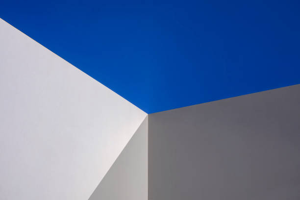 istock Sunlight and shadow on surface of white cement wall in perspective view against blue clear sky 1390659371