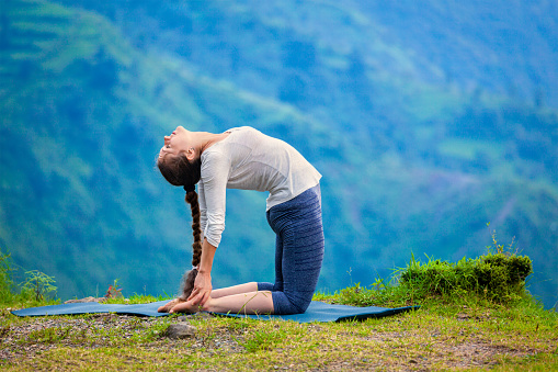 Yoga - outdoors young beautiful slender woman yoga instructor doing camel pose Ustrasana asana exercise outdoors
