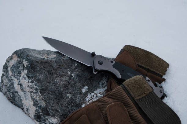 istock Tactical gloves and a folding knife in the snow. 1390661004