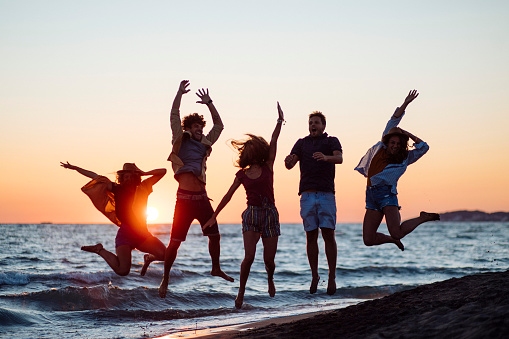 Photo of group of young people jumping on the beach