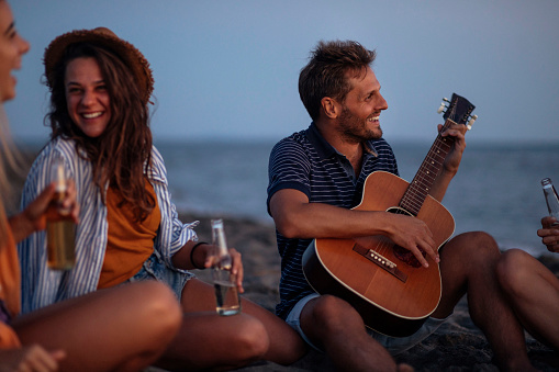 Sunset party on beach with friends and guitar