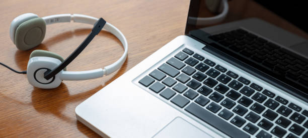 Headset and a laptop on a wooden table, view from above. Call center, home office, customer support, help desk concept