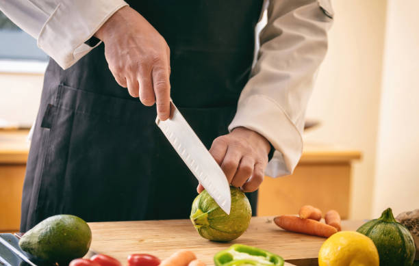 istock Chef cut zucchini with a knife on a chopping board, close up. Fresh vegetable on kitchen table. 1390663665