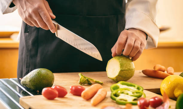 istock Chef cut zucchini with a knife on a chopping board, close up. Fresh vegetable on kitchen table. 1390663668