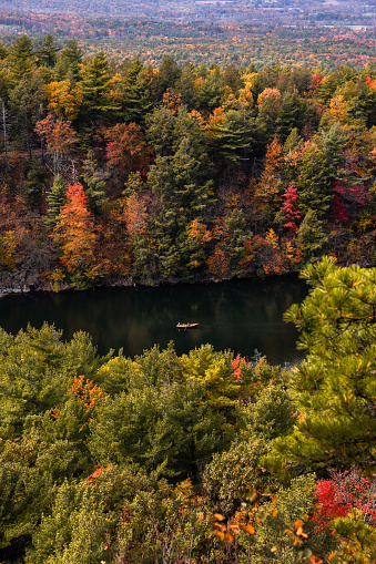 Small canoe on a peaceful lake, surrounded by colorful leaves and fall foliage. Mohonk Preserve, New York