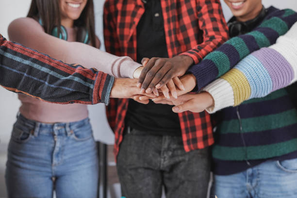 istock Young multiracial students stacking hands together - Team and generation z people concept 1390666032